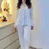 noom-pssps Pyjama satin blanc avec finitions rouges, élégant et confortable, parfait pour une tenue d'intérieur raffinée.