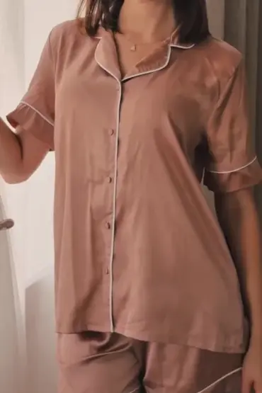 Pyjama satin rose doux avec finitions blanches, idéal pour une tenue d'intérieur élégante et confortable.