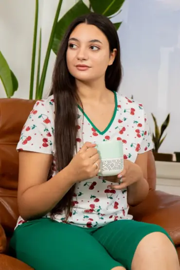Pyjama en coton léger blanc à motifs cerises, avec haut à col en V et bas vert, idéal pour une tenue d'intérieur confortable.