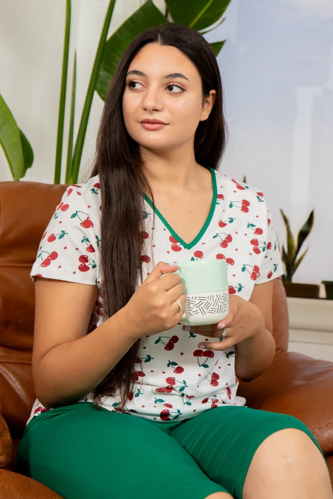 Pyjama en coton léger blanc à motifs cerises, avec haut à col en V et bas vert, idéal pour une tenue d'intérieur confortable.