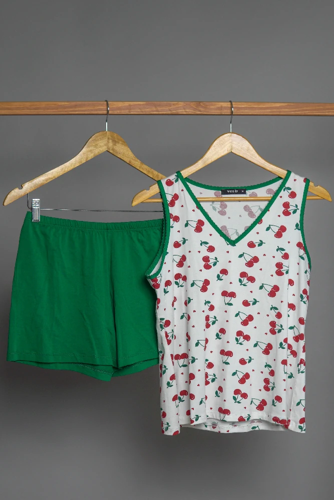 Pyjama doux en coton, haut blanc à motifs de cerises et short vert, idéal pour une tenue d'intérieur confortable et festive.