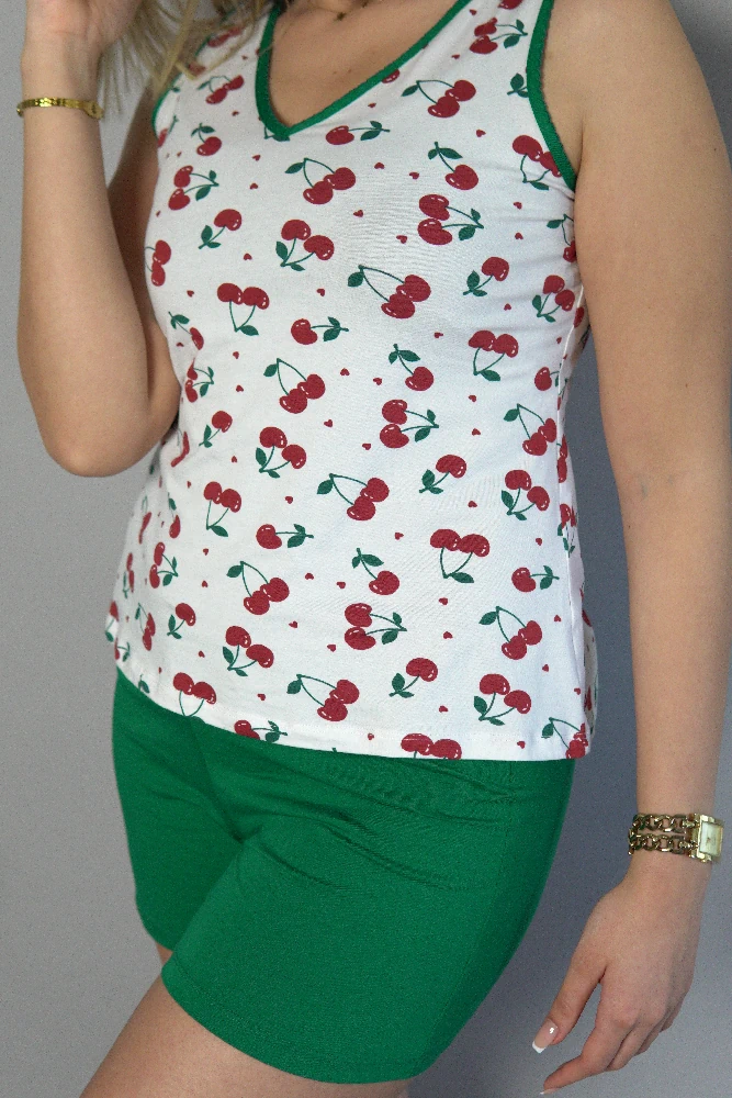 Ensemble de pyjama en coton doux, débardeur à motifs cerises et short vert, parfait pour une tenue d'intérieur confortable.