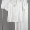 Ensemble de pyjama en satin blanc, léger et confortable, idéal pour une tenue d'intérieur élégante et relaxante.