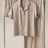 Ensemble pyjama en satin beige à rayures, confortable et élégant, parfait pour une tenue d'intérieur chic et luxueuse.
