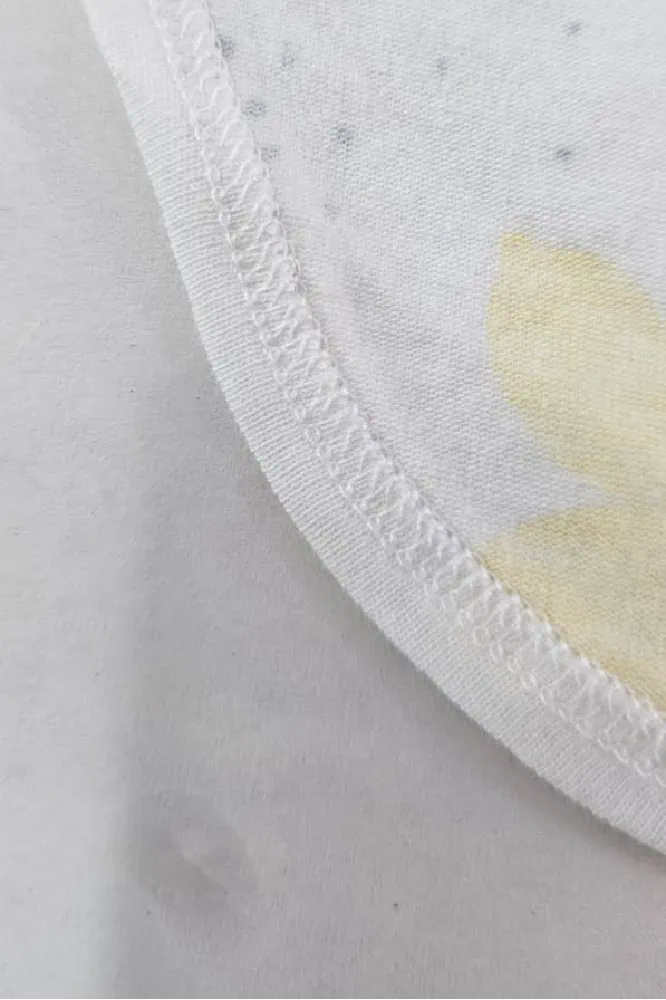Pyjama satin blanc doux avec motifs floraux, idéal pour une tenue d'intérieur chic et confortable.