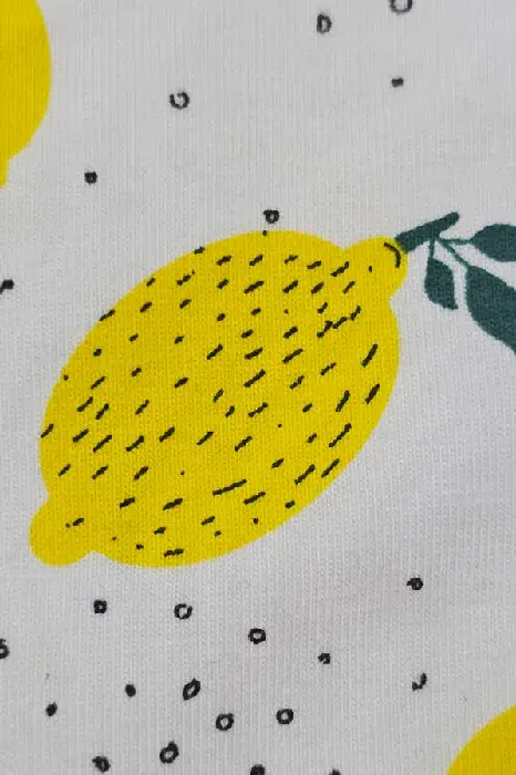Pyjama en coton doux avec motifs de citrons jaunes sur fond blanc, idéal pour une tenue d'intérieur confortable et estivale.