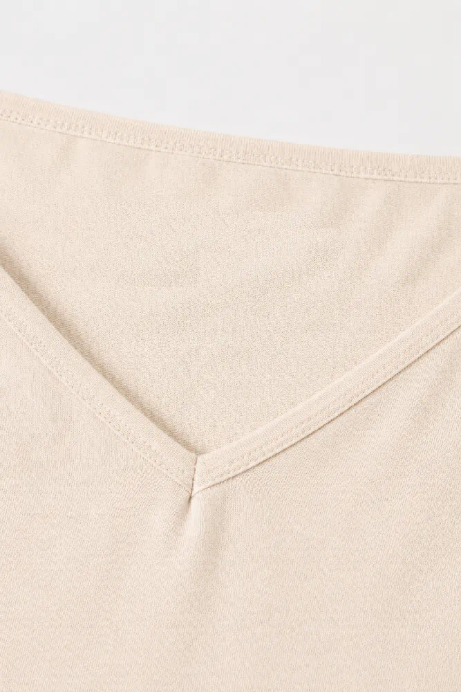 top-fines-bretelles-essential-col-beige Pyjama satin beige, doux et léger, avec un col en V pour un confort élégant, parfait pour la tenue d'intérieur.