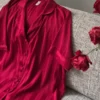 Pyjama satin rouge à rayures, haut léger et élégant, parfait pour une tenue d'intérieur chic et luxueuse.