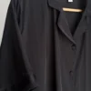 Pyjama satin noir élégant, style sophistiqué avec boutons, idéal pour une tenue d'intérieur luxueuse et confortable.