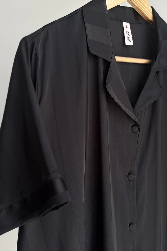 Pyjama satin noir élégant, style sophistiqué avec boutons, idéal pour une tenue d'intérieur luxueuse et confortable.