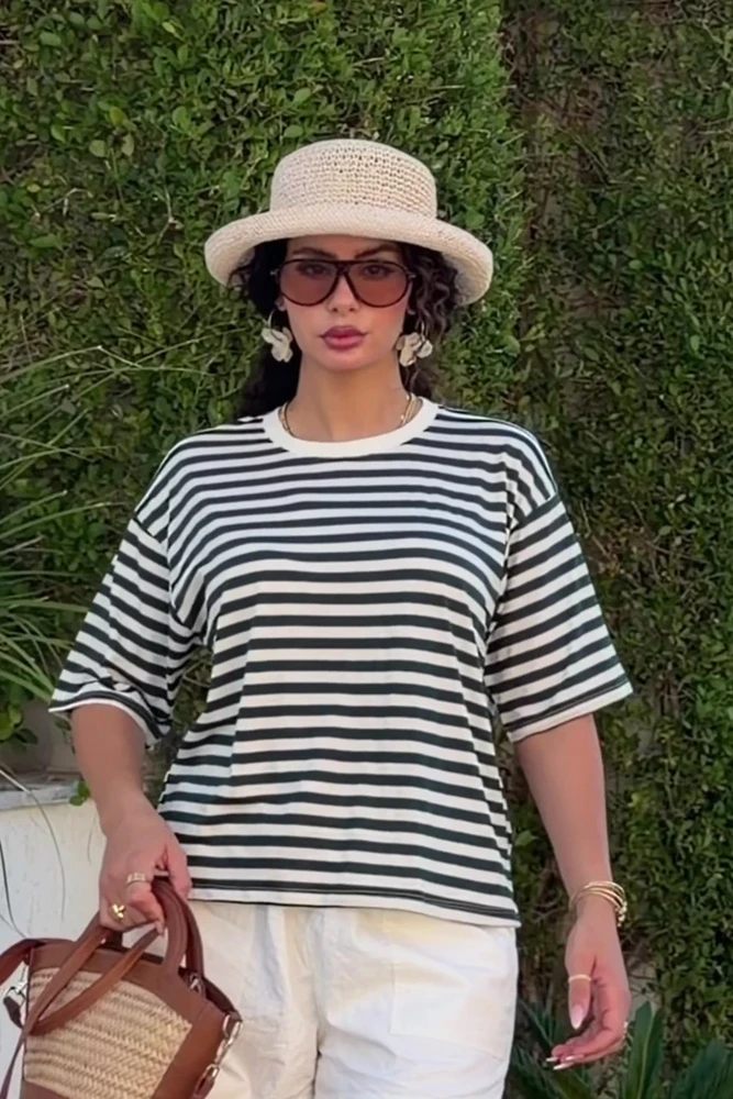 noom-green-stripe-lounge-tee-oversized-fullbody T-shirt rayé en coton doux, idéal comme tenue d'intérieur, associé à un pantalon blanc pour un look décontracté.